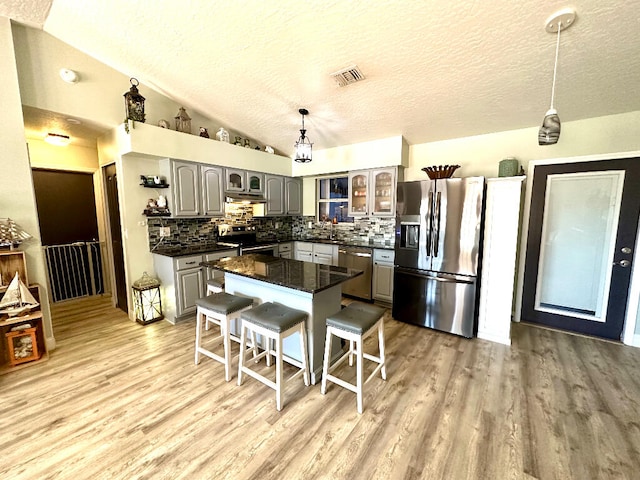 kitchen with light hardwood / wood-style flooring, stainless steel appliances, gray cabinets, a center island, and tasteful backsplash