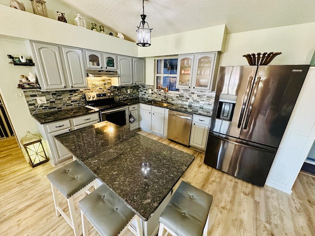 kitchen featuring stainless steel appliances, light hardwood / wood-style floors, gray cabinetry, tasteful backsplash, and a breakfast bar