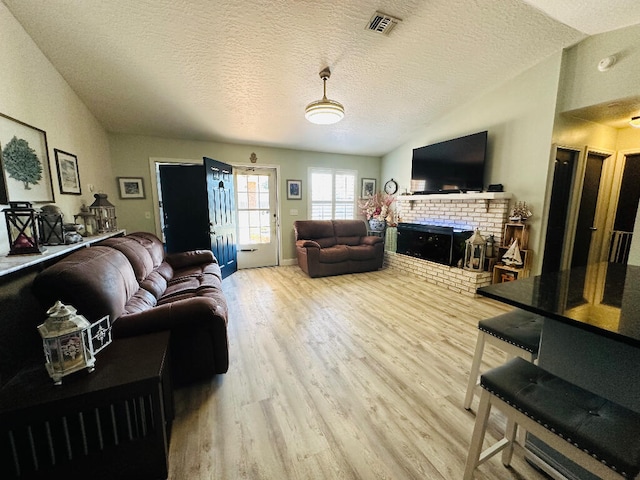 living room with vaulted ceiling, a fireplace, a textured ceiling, and hardwood / wood-style flooring