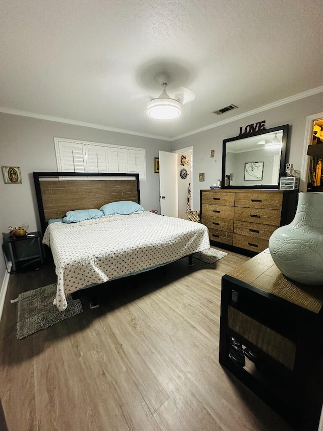 bedroom with a textured ceiling, hardwood / wood-style floors, ceiling fan, a spacious closet, and ornamental molding