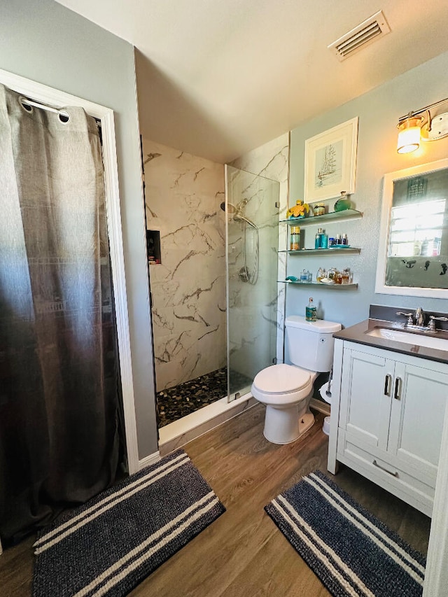 bathroom featuring vanity, a tile shower, toilet, and hardwood / wood-style floors