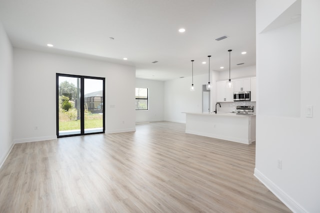 unfurnished living room with light wood-type flooring and sink