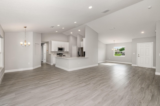 unfurnished living room with a chandelier, lofted ceiling, and light hardwood / wood-style flooring