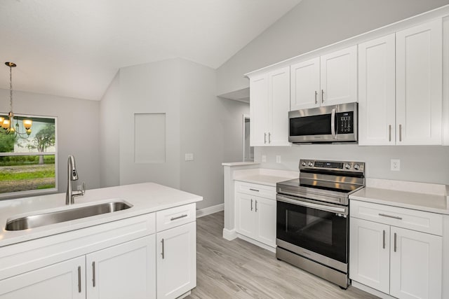 kitchen with pendant lighting, white cabinets, sink, vaulted ceiling, and appliances with stainless steel finishes