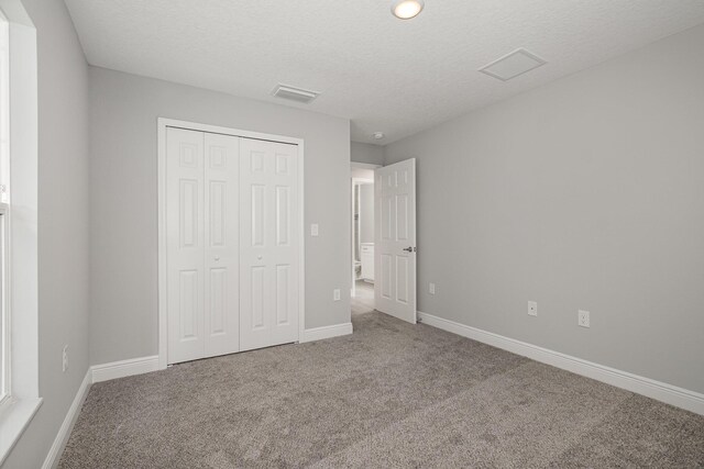 unfurnished bedroom with carpet, a textured ceiling, and a closet