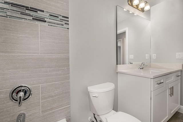 bathroom featuring vanity, a tile shower, and toilet