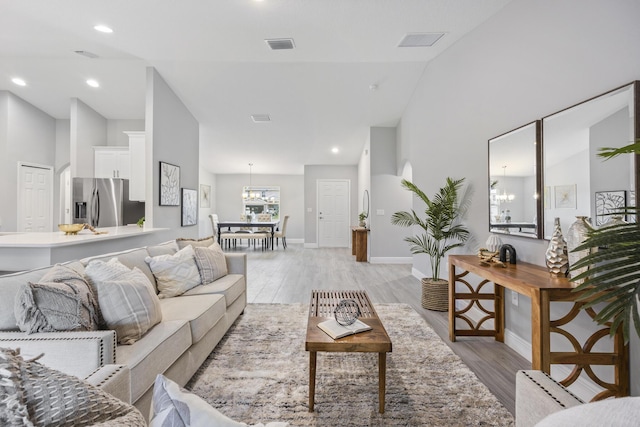 living room featuring an inviting chandelier, high vaulted ceiling, and light wood-type flooring