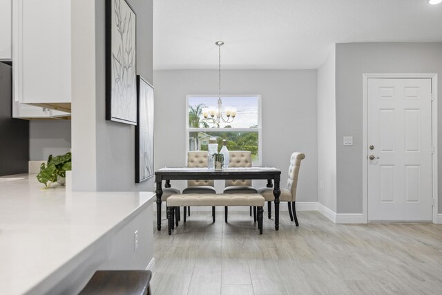 dining space with light hardwood / wood-style floors and a chandelier