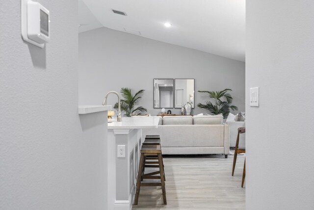 living room featuring light wood-type flooring and vaulted ceiling