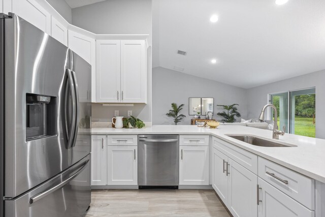 kitchen with white cabinetry, sink, stainless steel appliances, light hardwood / wood-style floors, and lofted ceiling