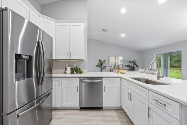 kitchen with sink, vaulted ceiling, light hardwood / wood-style flooring, appliances with stainless steel finishes, and white cabinets