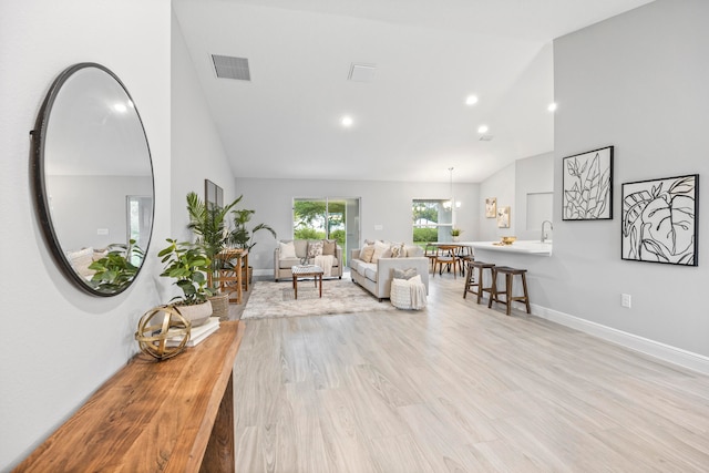 living room featuring sink, high vaulted ceiling, and light hardwood / wood-style floors