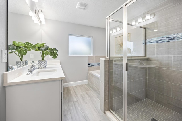 bathroom featuring hardwood / wood-style flooring, vanity, a textured ceiling, and independent shower and bath