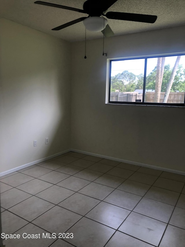 tiled empty room featuring a mountain view, a textured ceiling, and ceiling fan