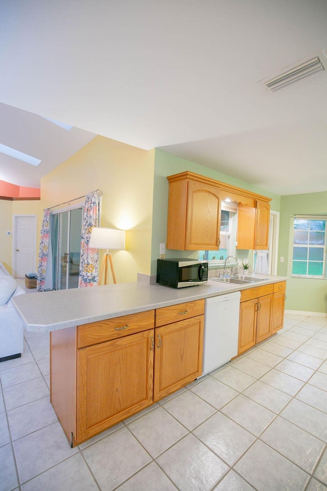 kitchen featuring dishwasher, light tile patterned floors, sink, and a skylight