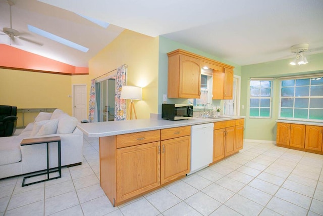 kitchen featuring ceiling fan, sink, kitchen peninsula, white dishwasher, and vaulted ceiling with skylight