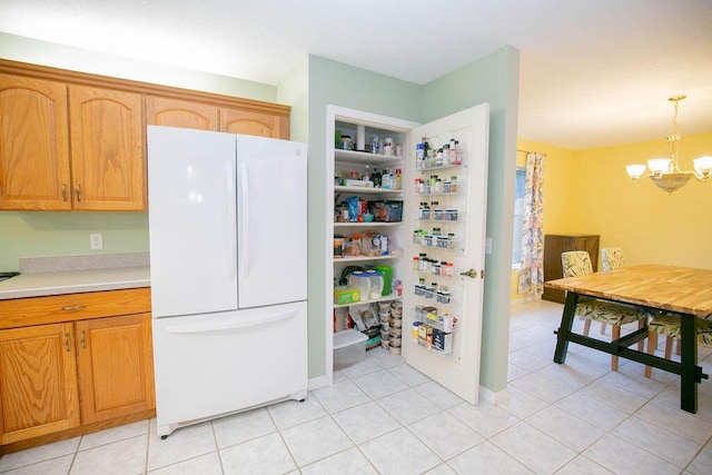 kitchen with white fridge, light tile patterned flooring, hanging light fixtures, and a chandelier