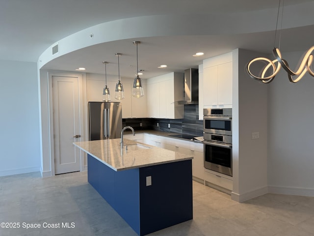 kitchen featuring decorative backsplash, wall chimney exhaust hood, modern cabinets, stainless steel appliances, and a sink