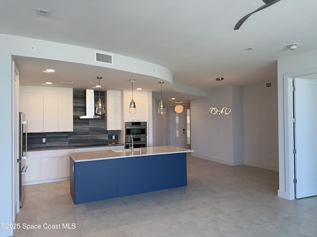 kitchen with visible vents, white cabinets, appliances with stainless steel finishes, backsplash, and wall chimney exhaust hood