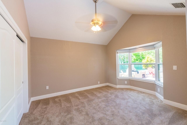 unfurnished bedroom featuring ceiling fan, a closet, light carpet, and lofted ceiling