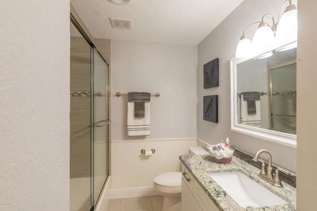 bathroom with toilet, vanity, a textured ceiling, and walk in shower