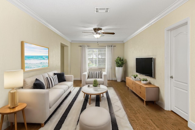 living room with wood-type flooring, ceiling fan, and crown molding