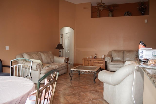 tiled living room with ceiling fan and a towering ceiling