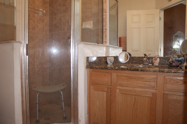 bathroom featuring a shower with shower door and vanity