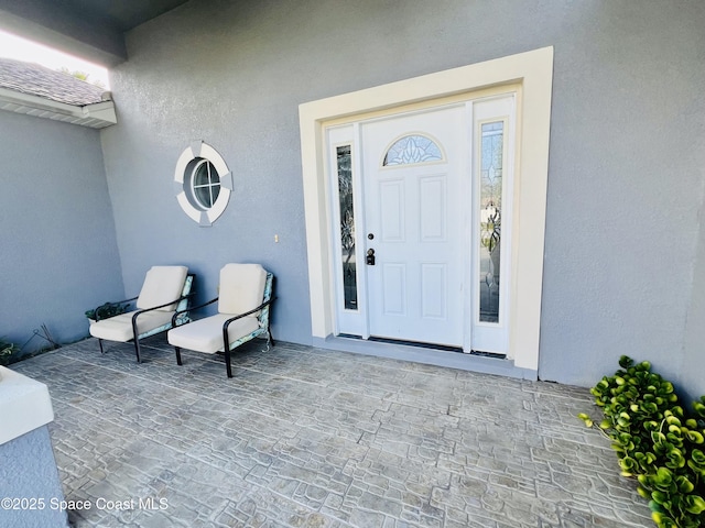 doorway to property featuring roof with shingles and stucco siding