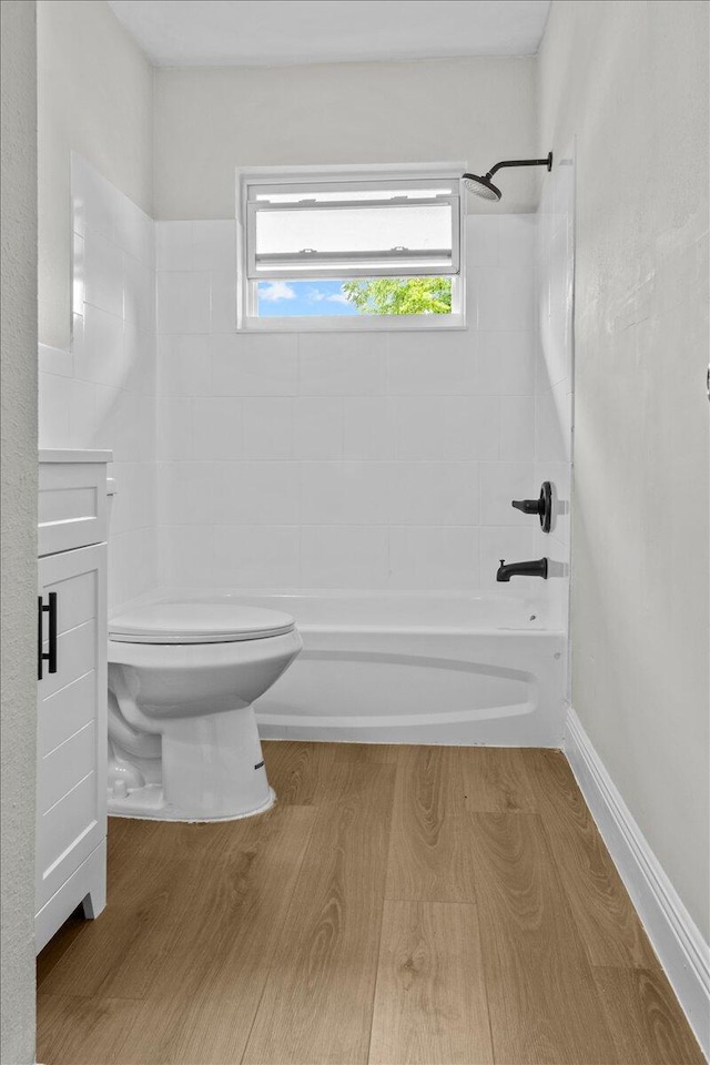 bathroom with toilet, tiled shower / bath combo, and hardwood / wood-style flooring