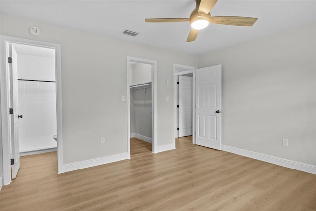 unfurnished bedroom with light wood-type flooring, a closet, a spacious closet, and ceiling fan