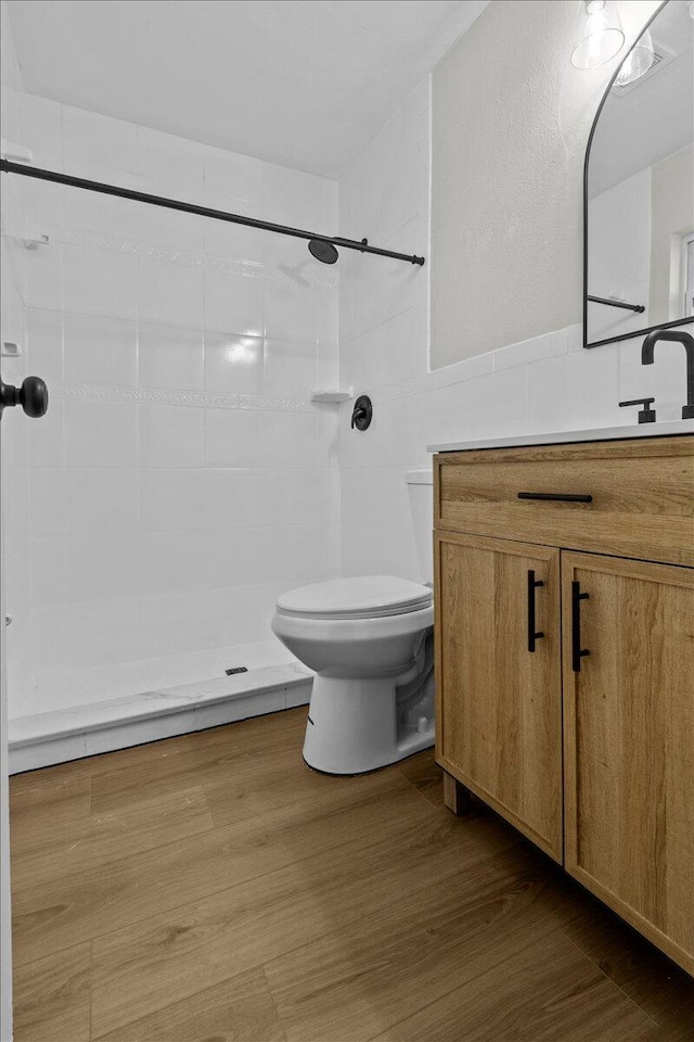 bathroom with vanity, toilet, wood-type flooring, and tiled shower