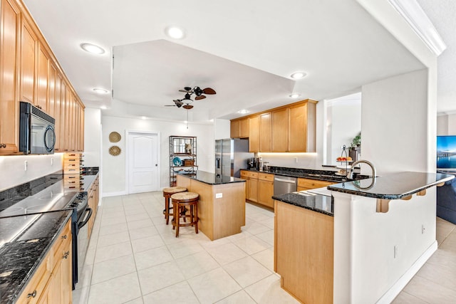 kitchen featuring a kitchen bar, stainless steel appliances, ceiling fan, light tile patterned floors, and a kitchen island