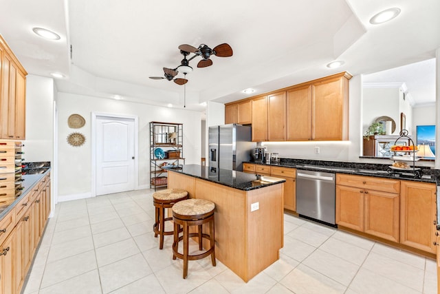 kitchen with appliances with stainless steel finishes, a center island, light tile patterned floors, and dark stone countertops