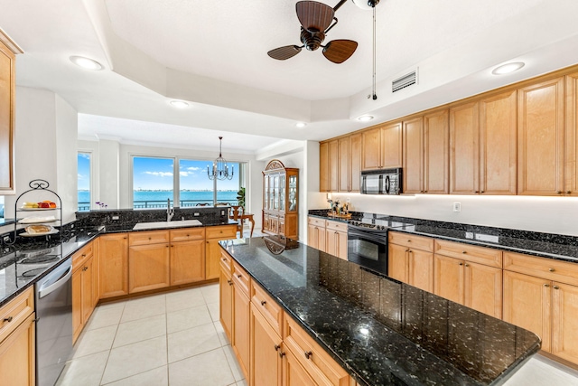 kitchen featuring a tray ceiling, sink, black appliances, and decorative light fixtures