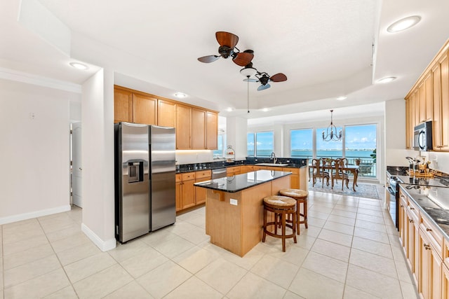 kitchen featuring ceiling fan with notable chandelier, stainless steel appliances, a center island, hanging light fixtures, and light tile patterned flooring