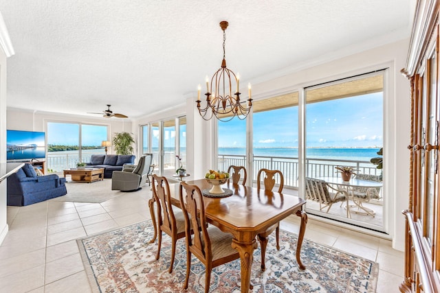 tiled dining room with a textured ceiling, ceiling fan with notable chandelier, and a water view