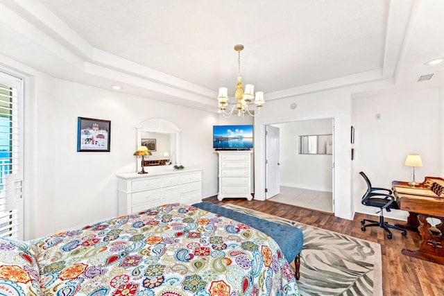 bedroom with a tray ceiling, an inviting chandelier, and light wood-type flooring