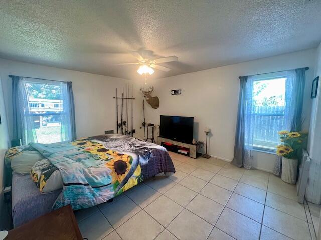 bedroom featuring light tile patterned floors, a textured ceiling, and ceiling fan