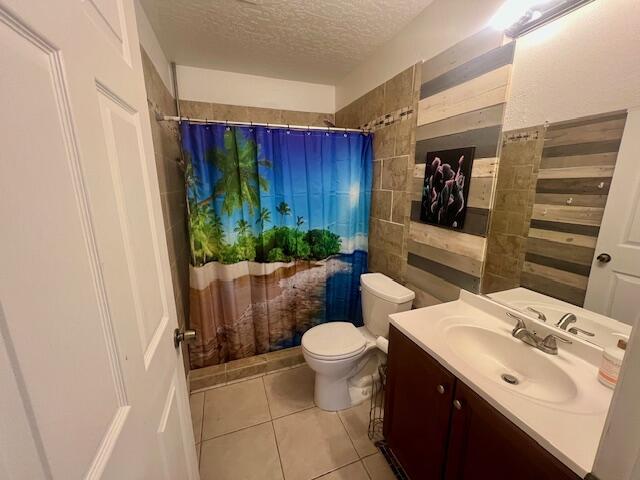 bathroom featuring vanity, a shower with curtain, tile patterned flooring, toilet, and a textured ceiling