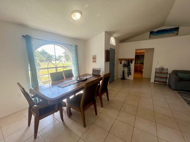 tiled dining room with a textured ceiling and vaulted ceiling