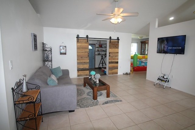 tiled living room featuring a barn door and ceiling fan