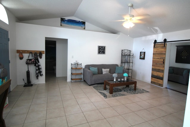 tiled living room featuring a barn door, vaulted ceiling, and ceiling fan