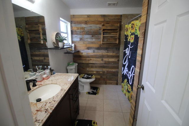 bathroom featuring vanity, tile patterned floors, wooden walls, toilet, and a textured ceiling