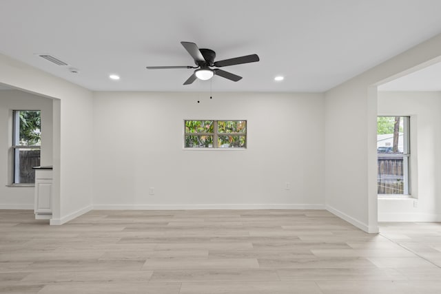 empty room featuring ceiling fan, light wood-type flooring, and a wealth of natural light