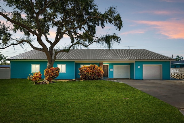 ranch-style home featuring a garage and a lawn