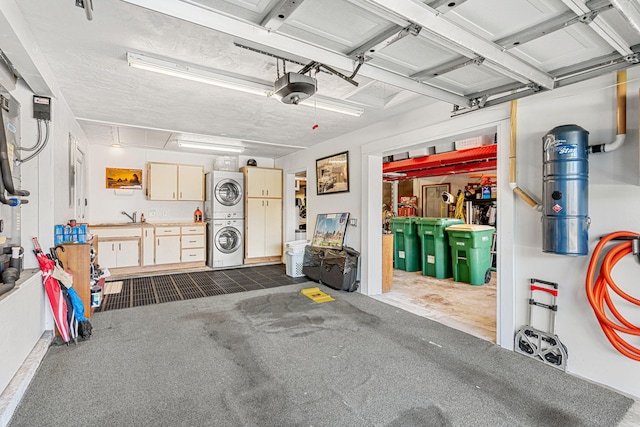 garage featuring a workshop area, sink, a garage door opener, and stacked washer and dryer