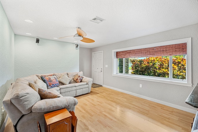 living room with plenty of natural light, ceiling fan, light hardwood / wood-style flooring, and a textured ceiling