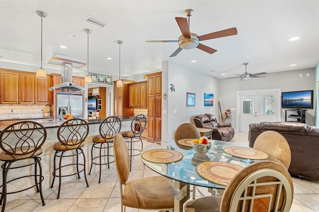 dining space featuring ceiling fan, a textured ceiling, and light tile floors