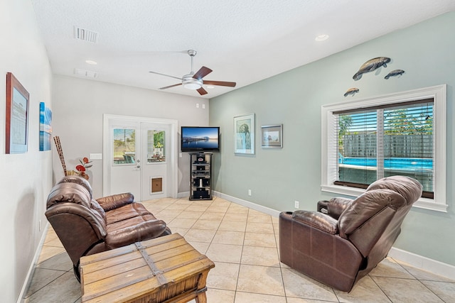 living room featuring a healthy amount of sunlight, a textured ceiling, ceiling fan, and light tile floors